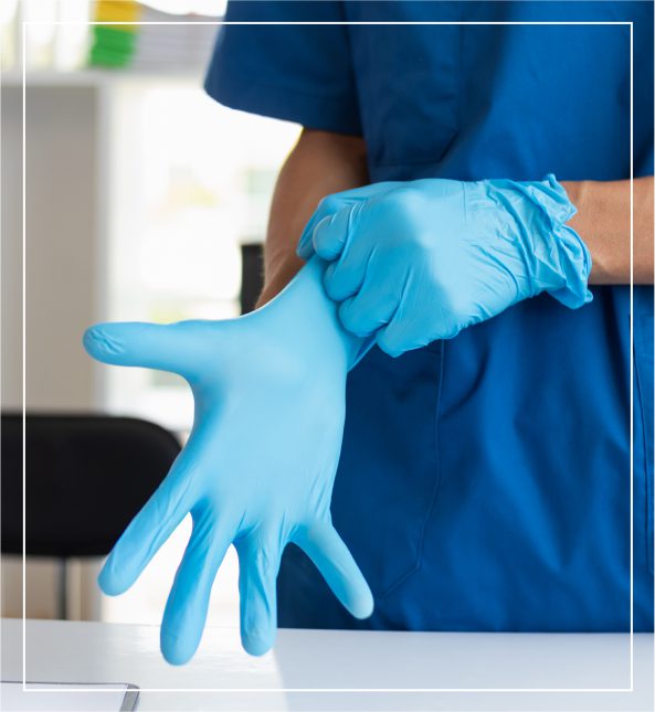 h2 (7) Person in blue scrubs putting on blue disposable gloves at a table.